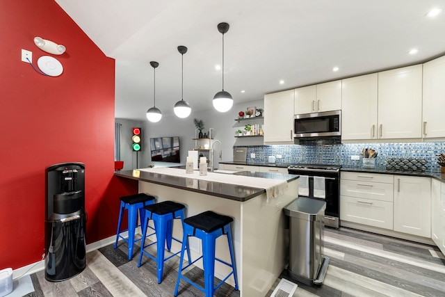 kitchen featuring decorative backsplash, range, hanging light fixtures, and white cabinets