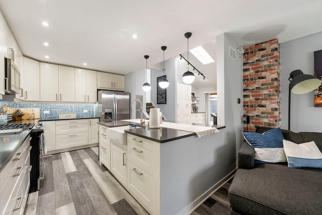 kitchen with pendant lighting, sink, hardwood / wood-style flooring, appliances with stainless steel finishes, and backsplash