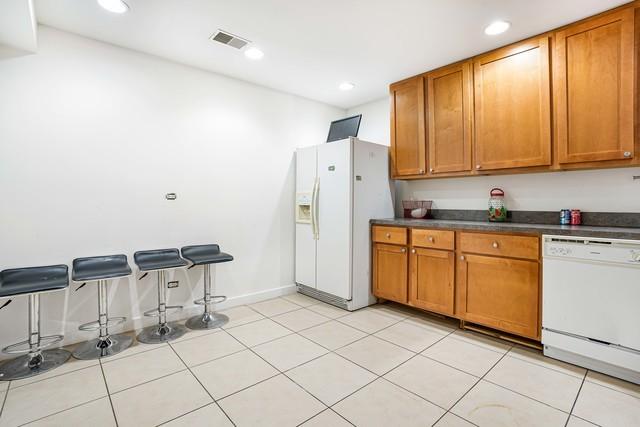 kitchen with white appliances, a breakfast bar, and light tile patterned floors