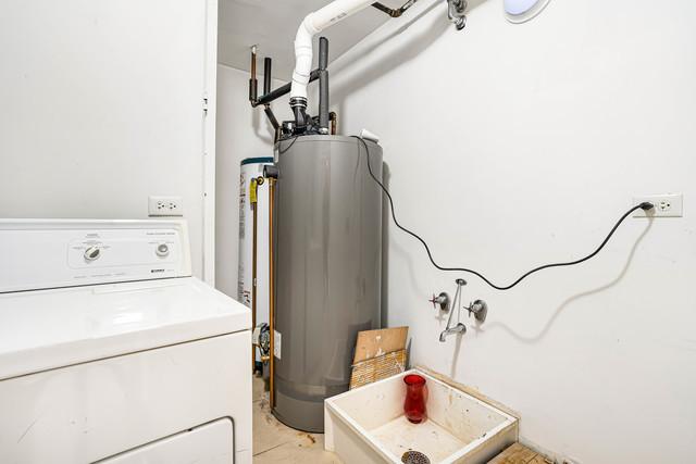 clothes washing area with washer / clothes dryer and water heater