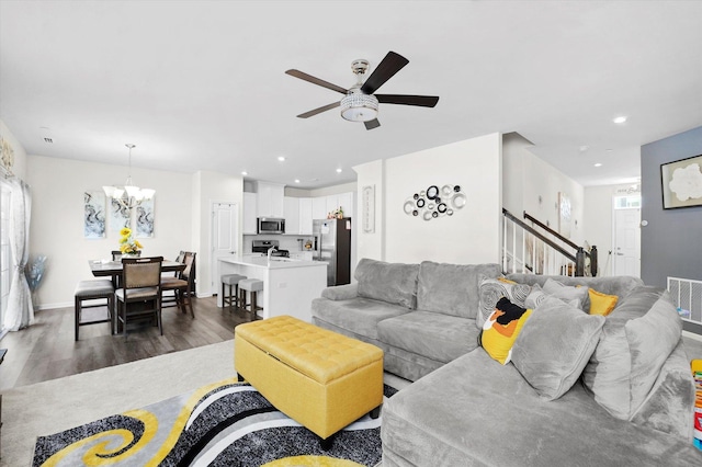 living room with ceiling fan with notable chandelier and dark hardwood / wood-style floors