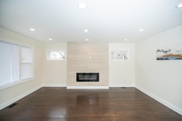 unfurnished living room featuring a large fireplace and dark hardwood / wood-style floors