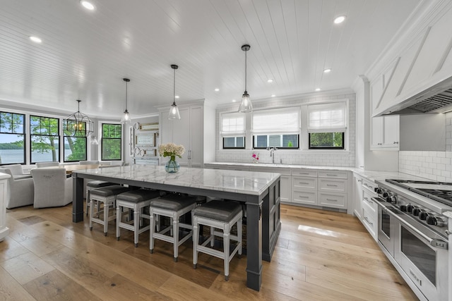 kitchen with white cabinets, a breakfast bar, a spacious island, and range with two ovens