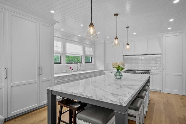 kitchen with white cabinetry, a kitchen bar, decorative light fixtures, and a center island