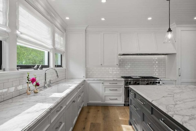 kitchen with pendant lighting, sink, white cabinets, high end range, and light stone counters