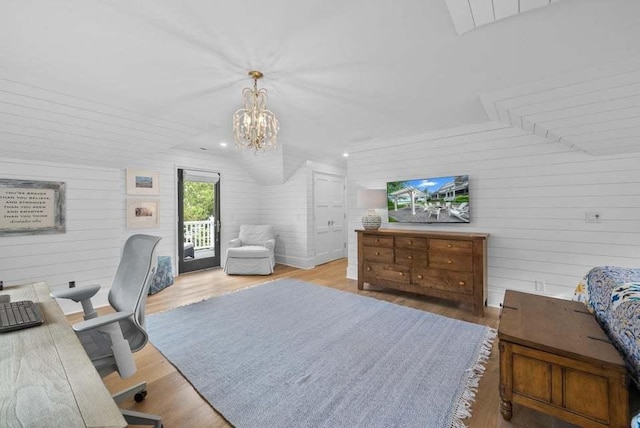 bedroom with an inviting chandelier, lofted ceiling, access to exterior, and light hardwood / wood-style floors