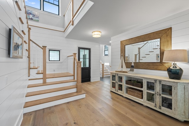 foyer with a wealth of natural light, wood walls, and light hardwood / wood-style flooring