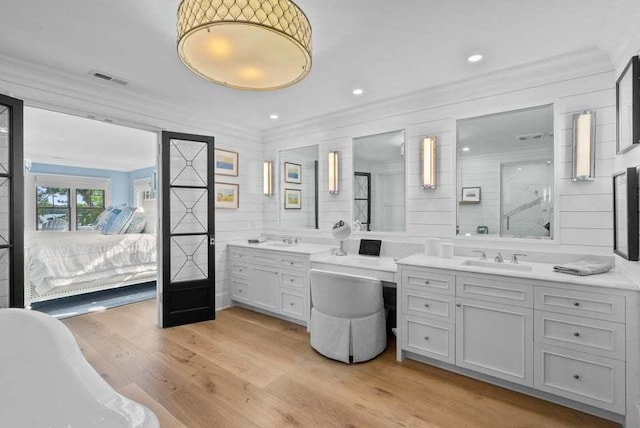 bathroom featuring ornamental molding, hardwood / wood-style floors, vanity, and a bathtub