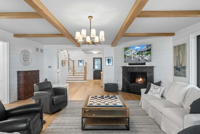 living room featuring a premium fireplace, beamed ceiling, and light wood-type flooring