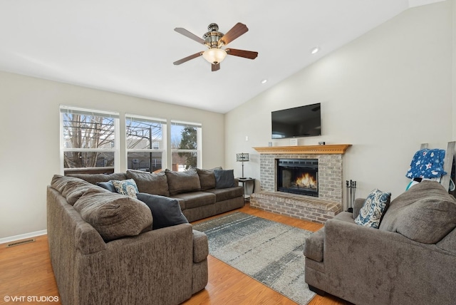 living room with a fireplace, ceiling fan, high vaulted ceiling, and light hardwood / wood-style floors