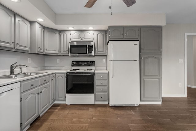 kitchen with white appliances, dark wood-style flooring, a sink, light countertops, and gray cabinets