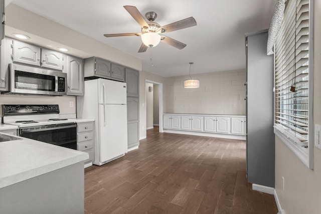 kitchen with dark wood-type flooring, range with electric stovetop, light countertops, freestanding refrigerator, and stainless steel microwave