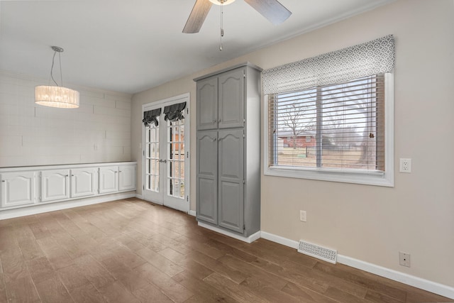 unfurnished room with a ceiling fan, dark wood-style flooring, visible vents, and baseboards