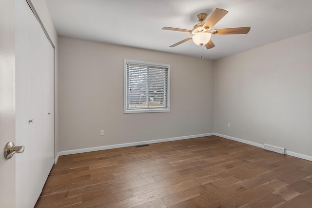 spare room with visible vents, ceiling fan, baseboards, and wood finished floors