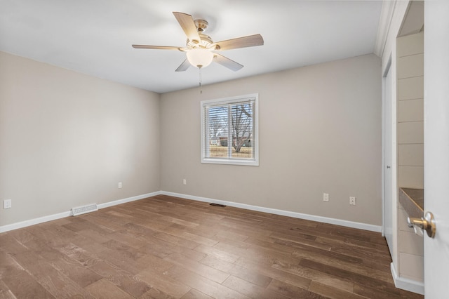 empty room featuring baseboards, visible vents, ceiling fan, and wood finished floors