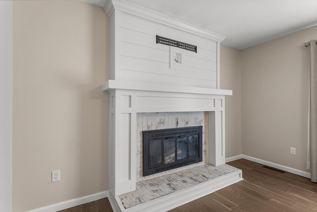 interior details with wood finished floors, a glass covered fireplace, visible vents, and baseboards