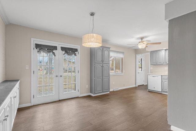 unfurnished dining area with dark wood-style floors, ceiling fan, baseboards, and french doors