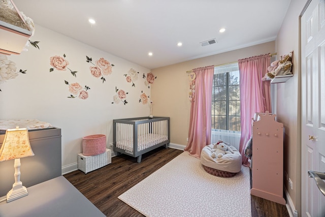 bedroom with a nursery area and dark hardwood / wood-style floors