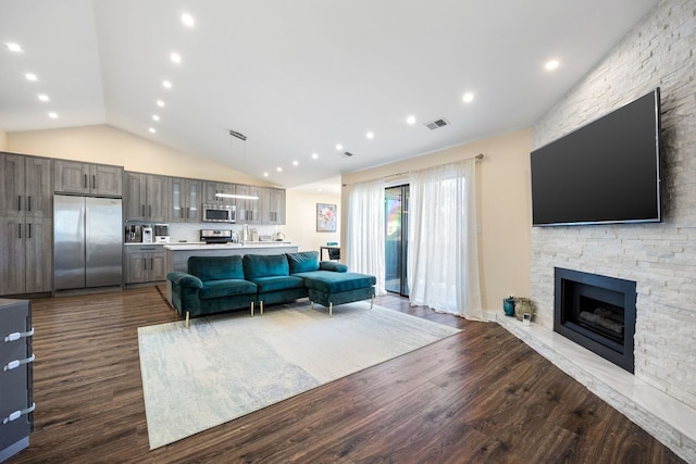 living room featuring lofted ceiling, a stone fireplace, and dark hardwood / wood-style floors