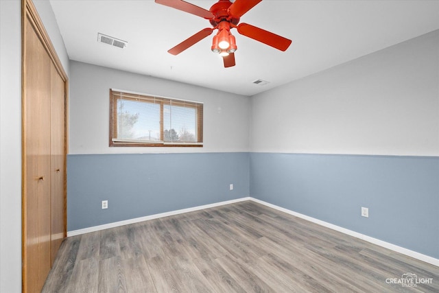 unfurnished bedroom featuring hardwood / wood-style floors, a closet, and ceiling fan