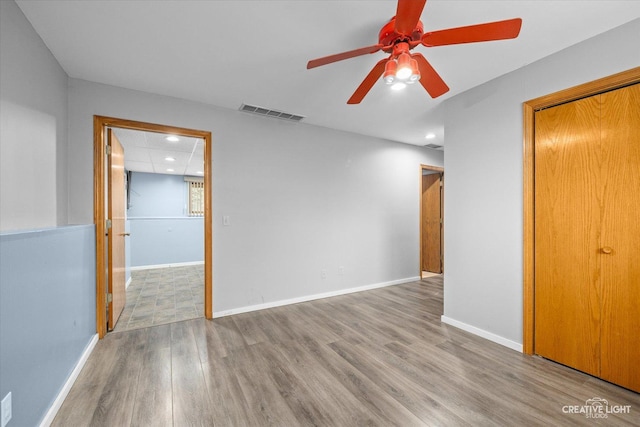 spare room with a drop ceiling, ceiling fan, and light hardwood / wood-style flooring