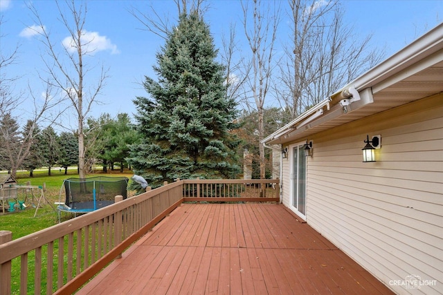 wooden deck with a playground, a trampoline, and a lawn