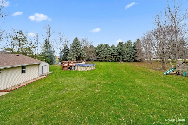 view of yard featuring a playground, a covered pool, and a storage unit