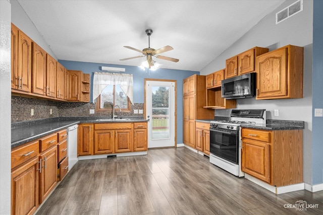 kitchen featuring dark wood-type flooring, lofted ceiling, sink, gas stove, and white dishwasher