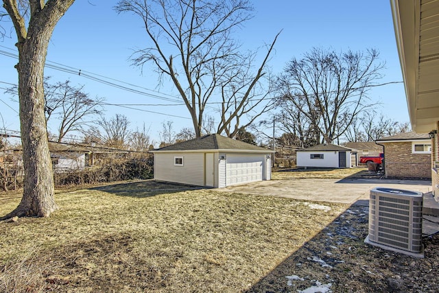 view of yard with a garage, an outbuilding, and central AC unit