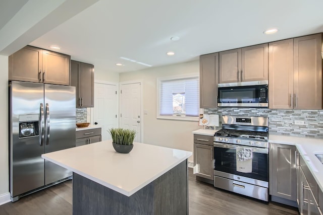 kitchen featuring tasteful backsplash, stainless steel appliances, a center island, and dark wood-type flooring