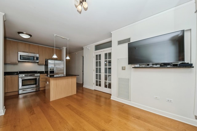 kitchen featuring a kitchen bar, a center island, hanging light fixtures, light hardwood / wood-style flooring, and appliances with stainless steel finishes