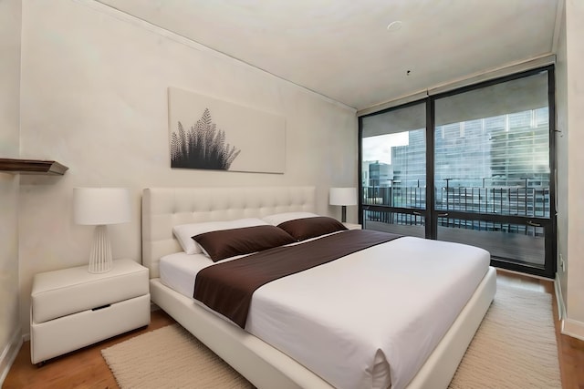 bedroom featuring access to outside, light hardwood / wood-style floors, and floor to ceiling windows