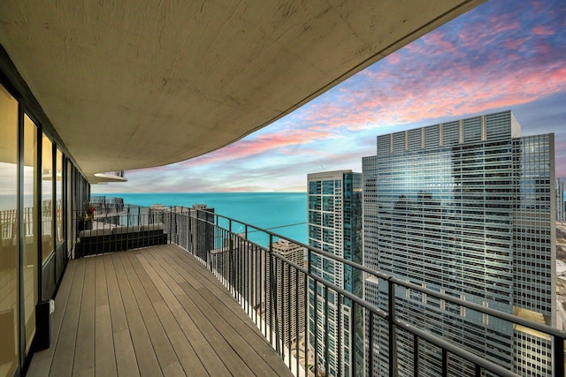 balcony at dusk featuring a water view