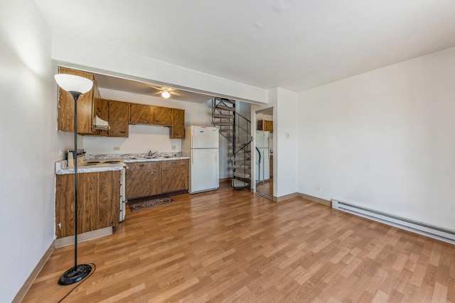 kitchen featuring freestanding refrigerator, light countertops, light wood finished floors, and electric range oven