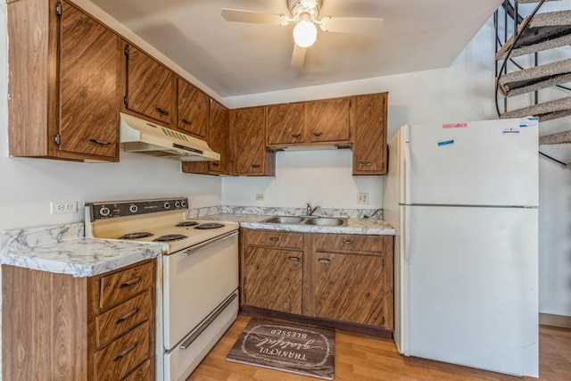 kitchen featuring light countertops, white appliances, a sink, and under cabinet range hood