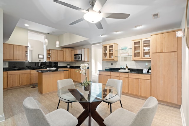 kitchen with hanging light fixtures, light wood-type flooring, light brown cabinets, and a kitchen island