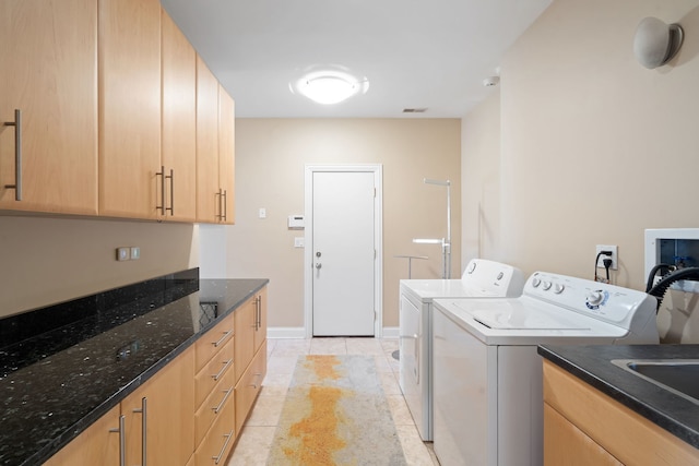 washroom with light tile patterned floors, washer and clothes dryer, and cabinets