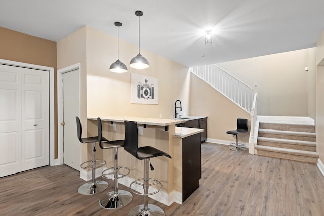 kitchen featuring sink, a breakfast bar area, pendant lighting, kitchen peninsula, and hardwood / wood-style flooring