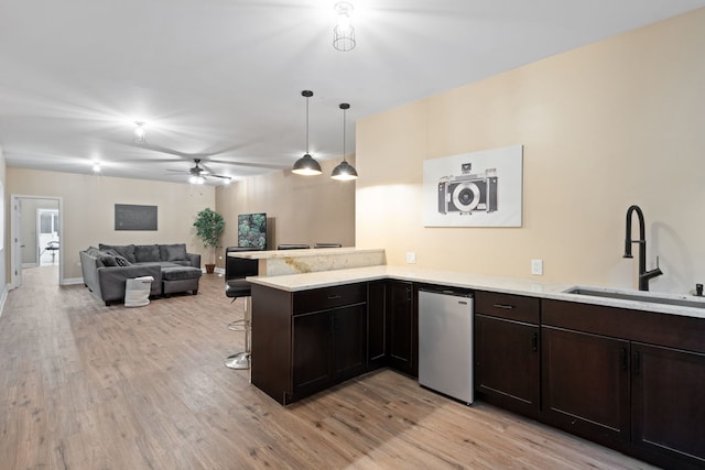 kitchen with sink, decorative light fixtures, light wood-type flooring, a kitchen breakfast bar, and kitchen peninsula