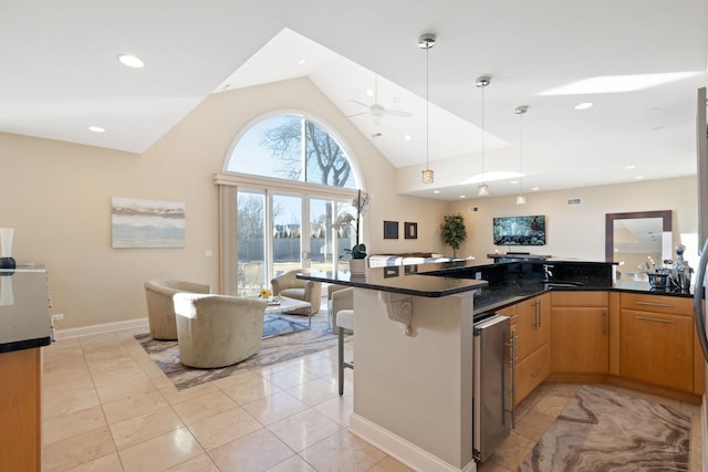 kitchen featuring wine cooler, a kitchen bar, decorative light fixtures, dark stone countertops, and ceiling fan