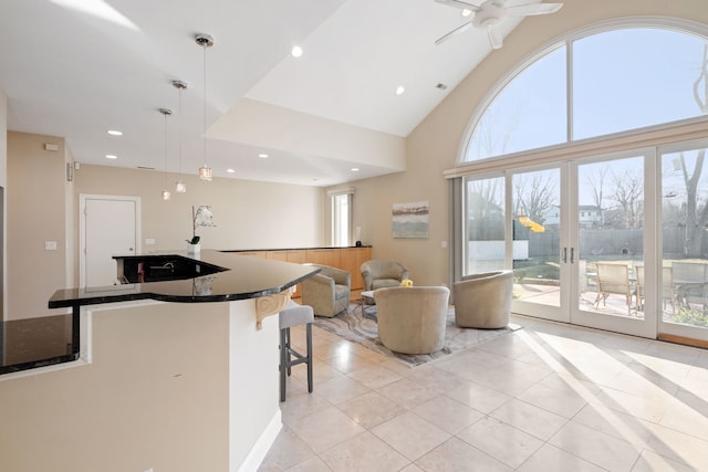 kitchen with pendant lighting, high vaulted ceiling, a breakfast bar area, light tile patterned floors, and ceiling fan