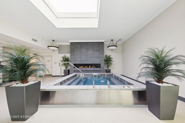 view of pool with a large fireplace, a skylight, and an indoor hot tub