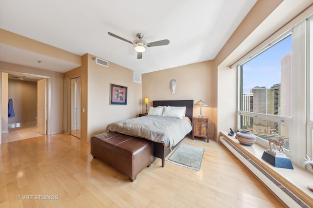 bedroom featuring light hardwood / wood-style flooring, ceiling fan, and baseboard heating