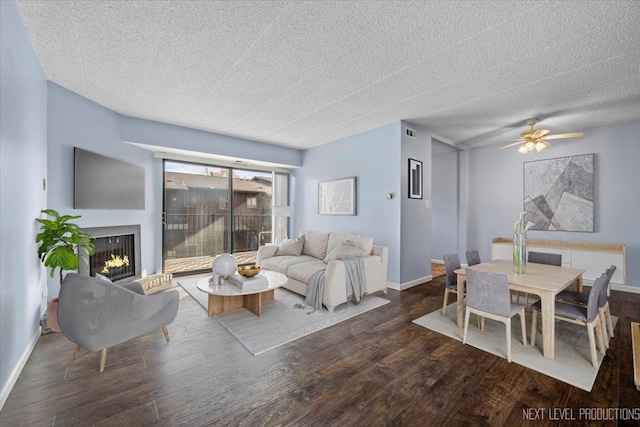 living room featuring ceiling fan, dark wood-type flooring, and a textured ceiling