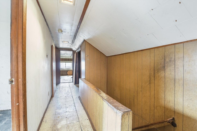 hallway featuring lofted ceiling and wooden walls