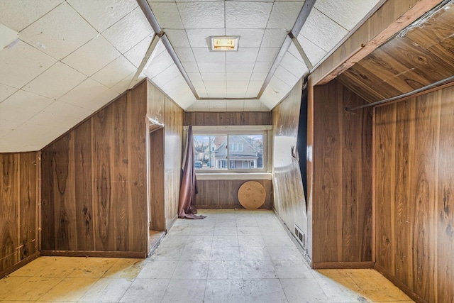 additional living space featuring lofted ceiling and wooden walls