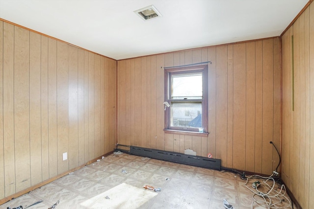 unfurnished room featuring wooden walls and a baseboard heating unit