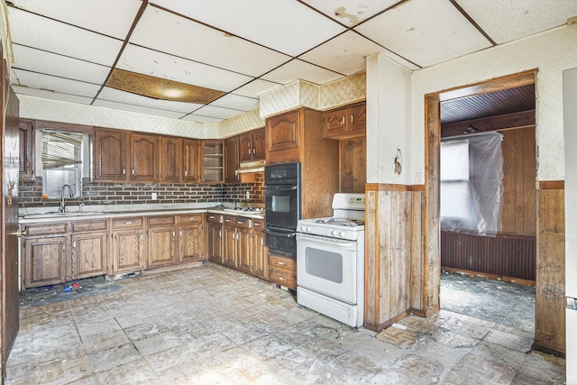 kitchen with sink, white gas stove, wood walls, tasteful backsplash, and a paneled ceiling