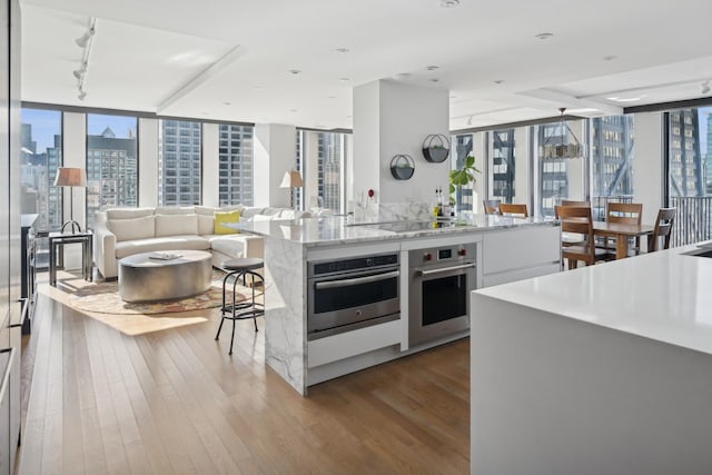 kitchen with hardwood / wood-style flooring, stainless steel oven, black electric stovetop, and white cabinets