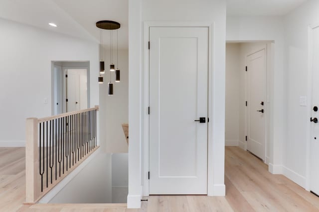 hall with recessed lighting, light wood finished floors, baseboards, and an upstairs landing